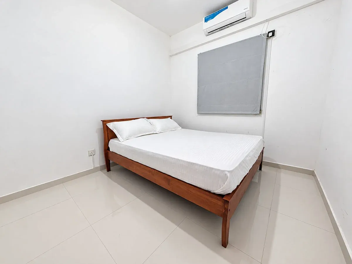 Second bedroom with queen bed, air-conditioned, with grey window shade and white bedding