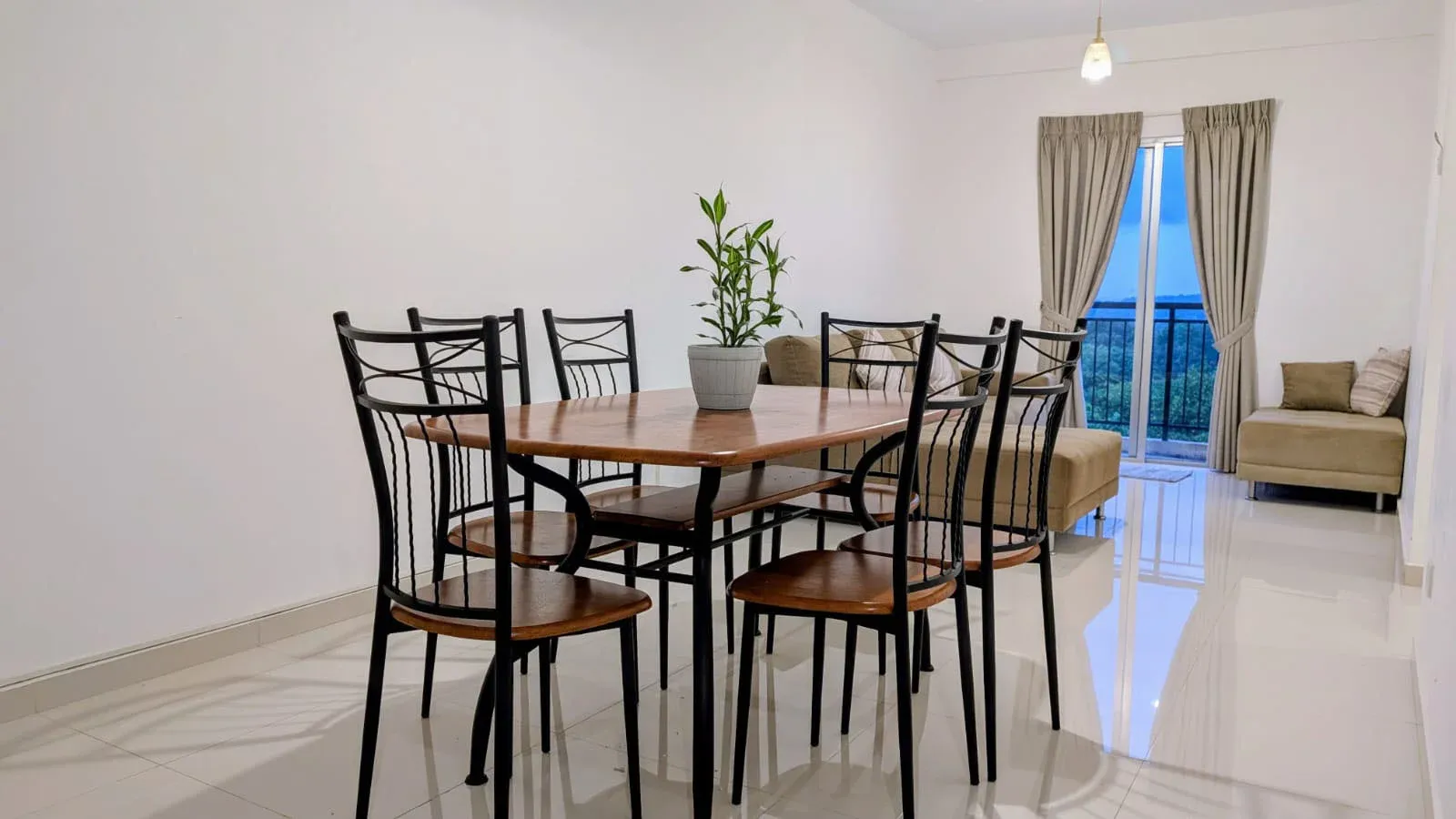 Living and dining area at Greenview Apartment with sofa, dining table and balcony doors overlooking green hills